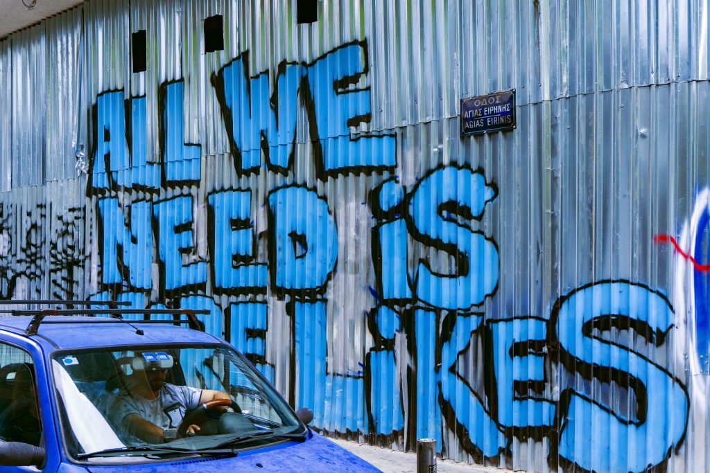 Graffiti on wall says "All we need is likes"
